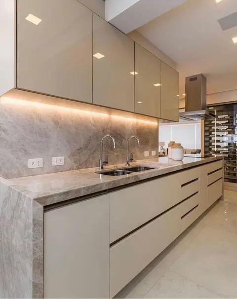 Bancada de cozinha e frontão em pedra natural de veios suaves, com cuba dupla e luz embaixo dos armários
