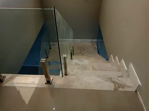 Degraus em pedra clara com guarda-corpo de vidro